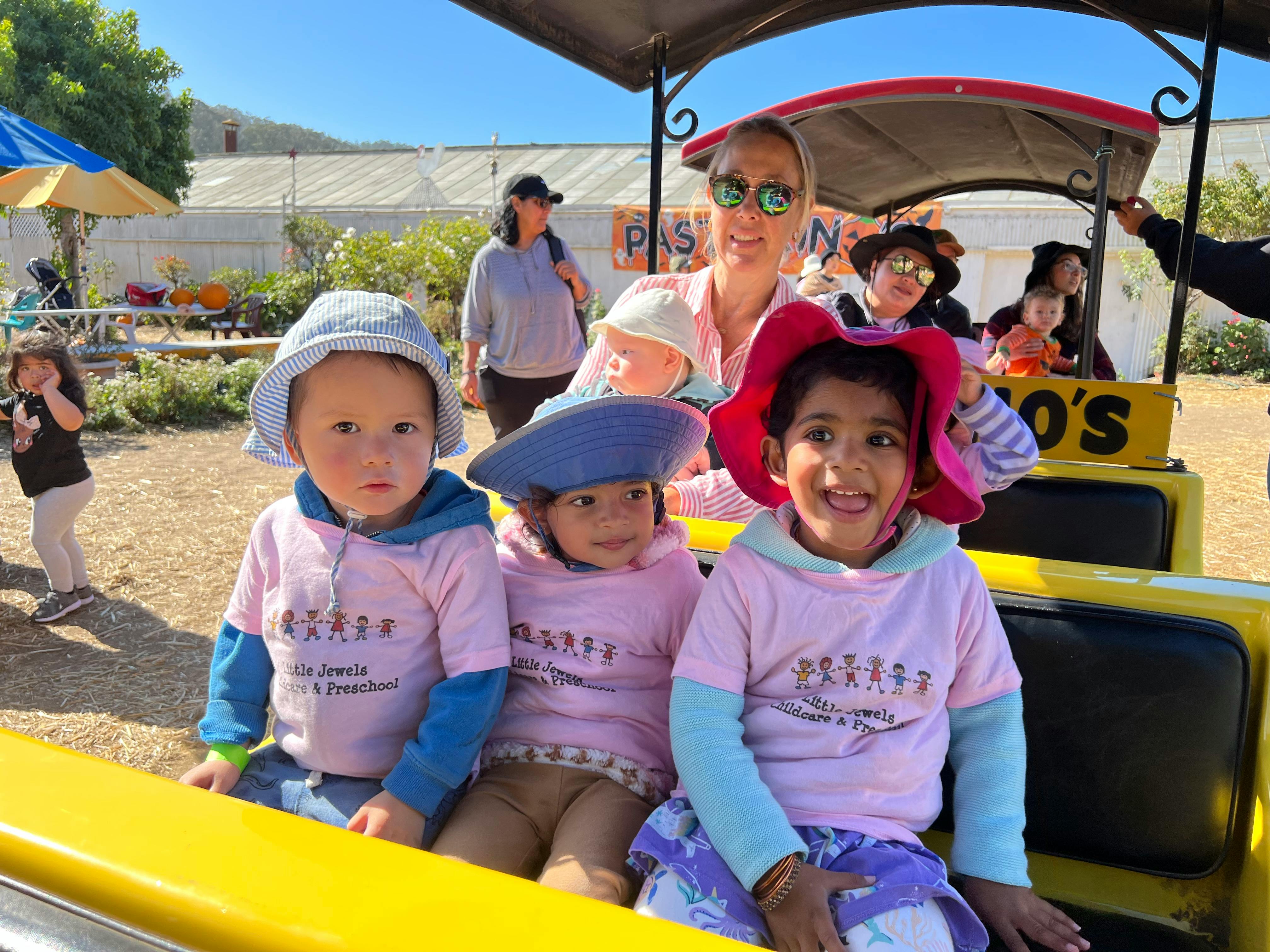 Three children and an adult riding in a yellow vehicle