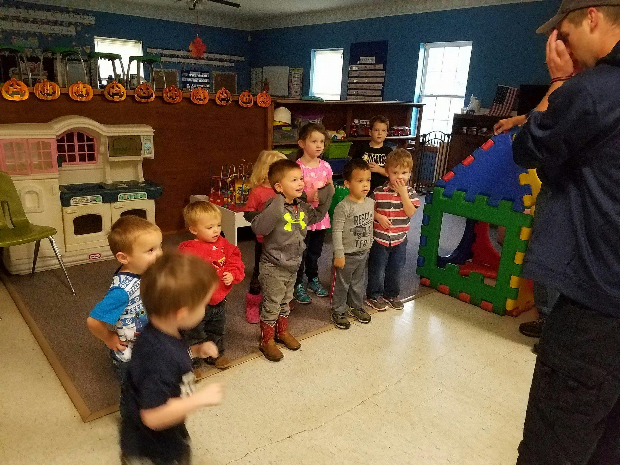 Adult speaking to a group of children in a classroom