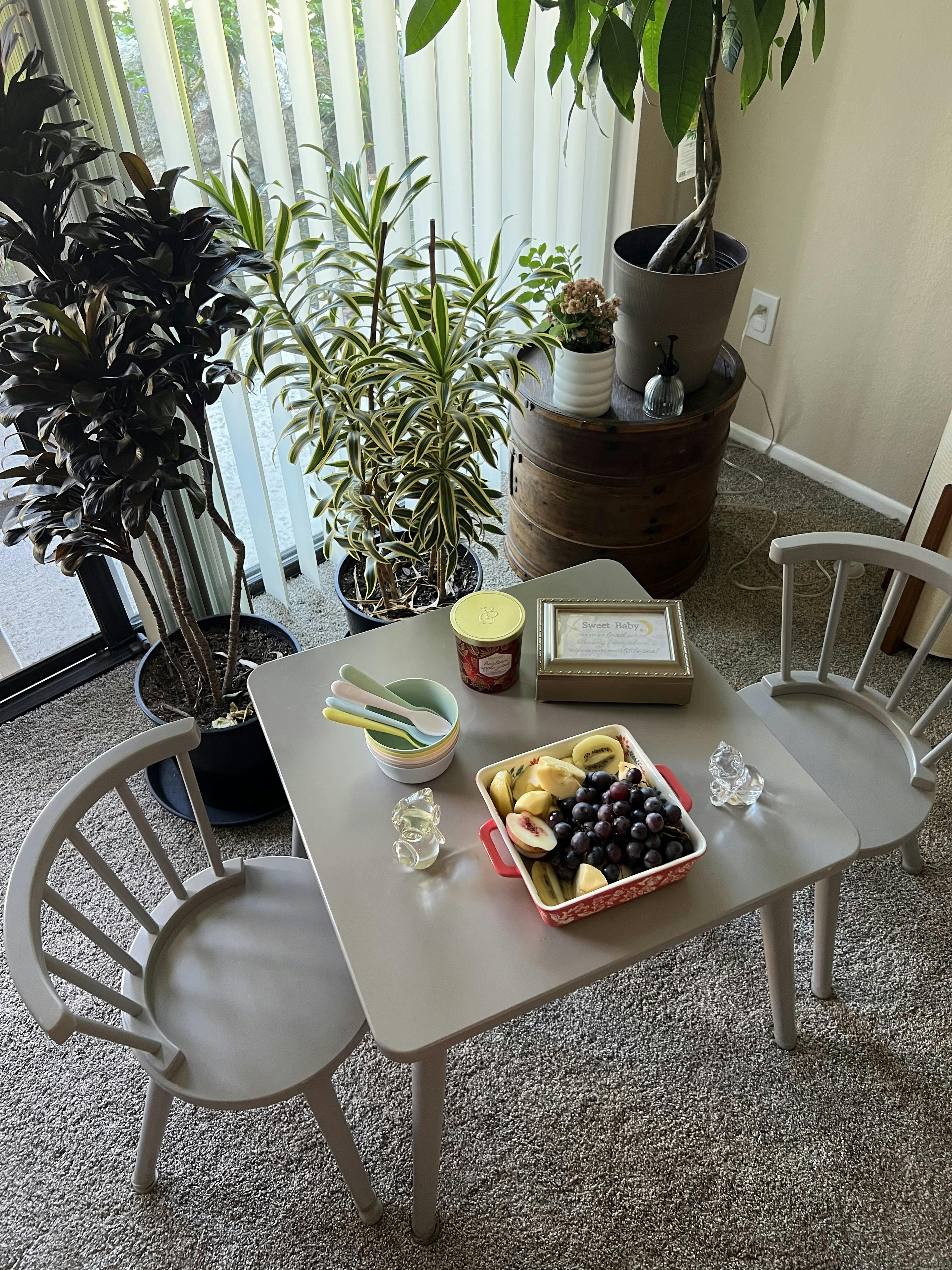 Small table with chairs holding a tray of sliced fruit and bowls with spoons
