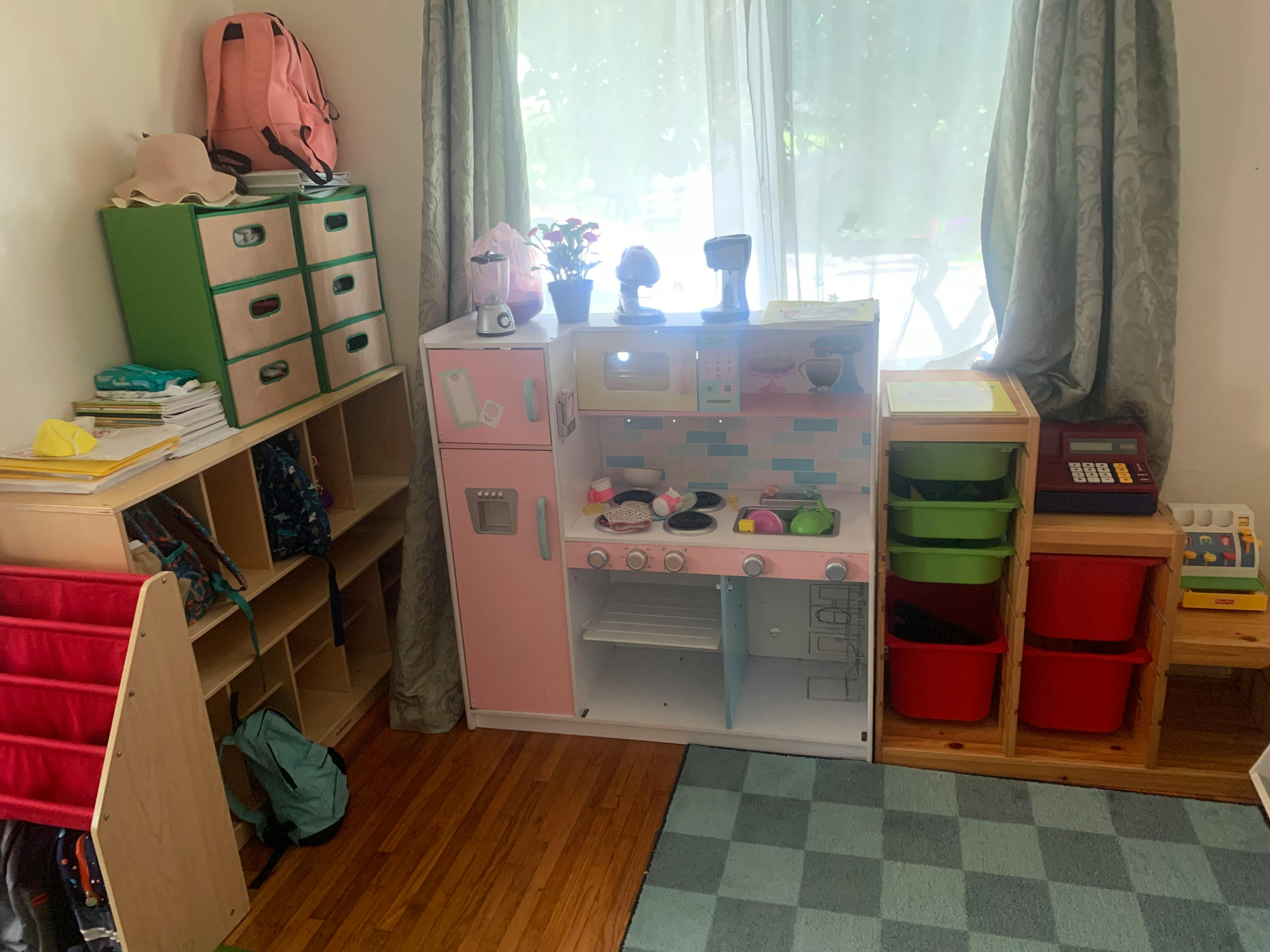 Playroom with toy kitchen, shelves, and storage bins