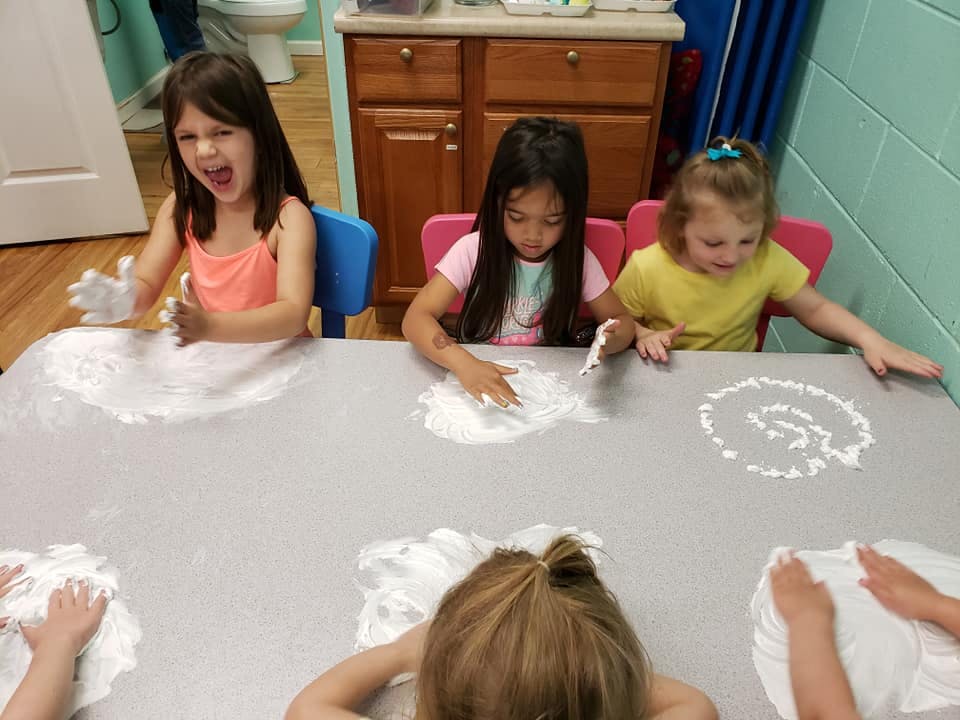 Children playing with white foam on a table
