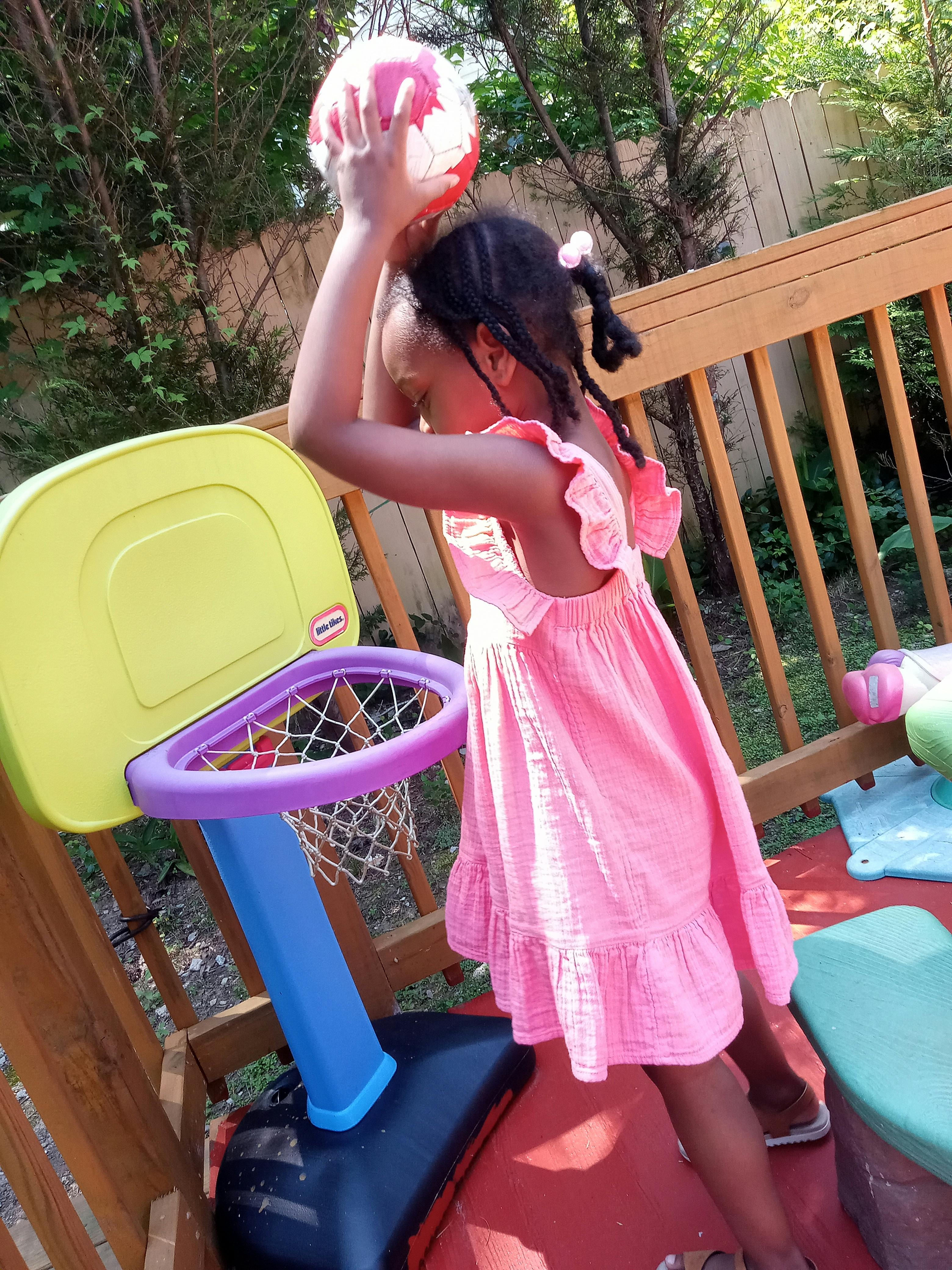 Child playing with a basketball and a toy hoop
