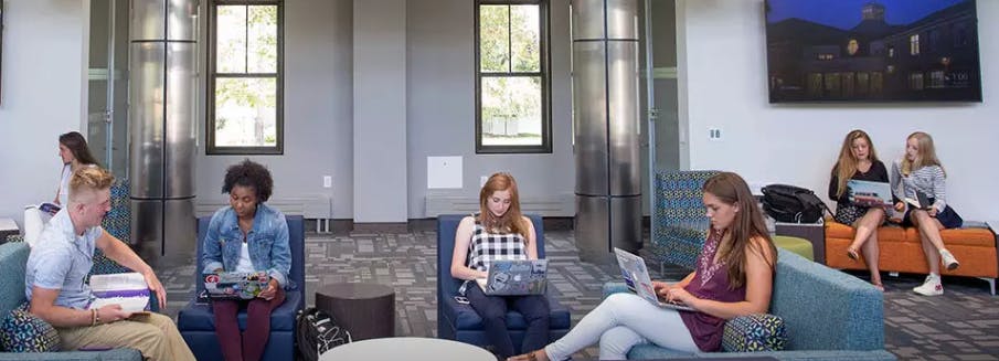 People sitting in chairs and on a bench, some using laptops