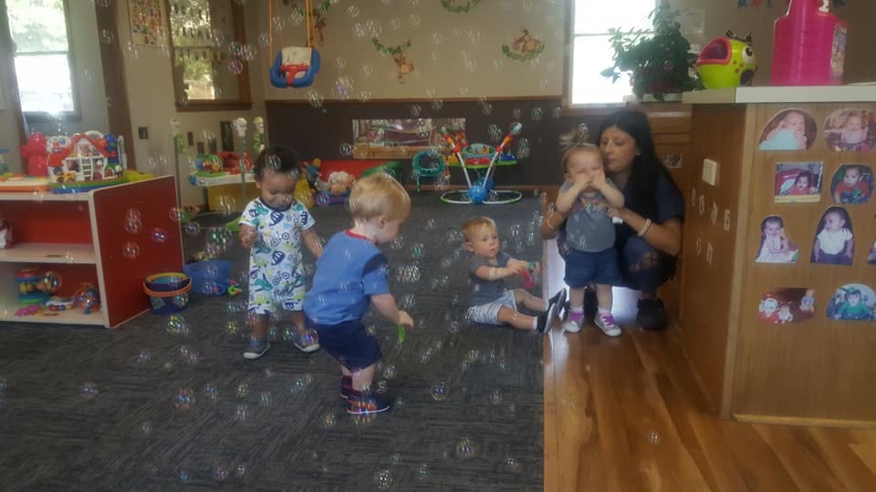 Adult and children playing with bubbles in a classroom
