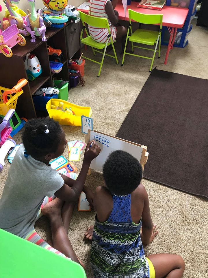 Two children drawing on a whiteboard on the floor