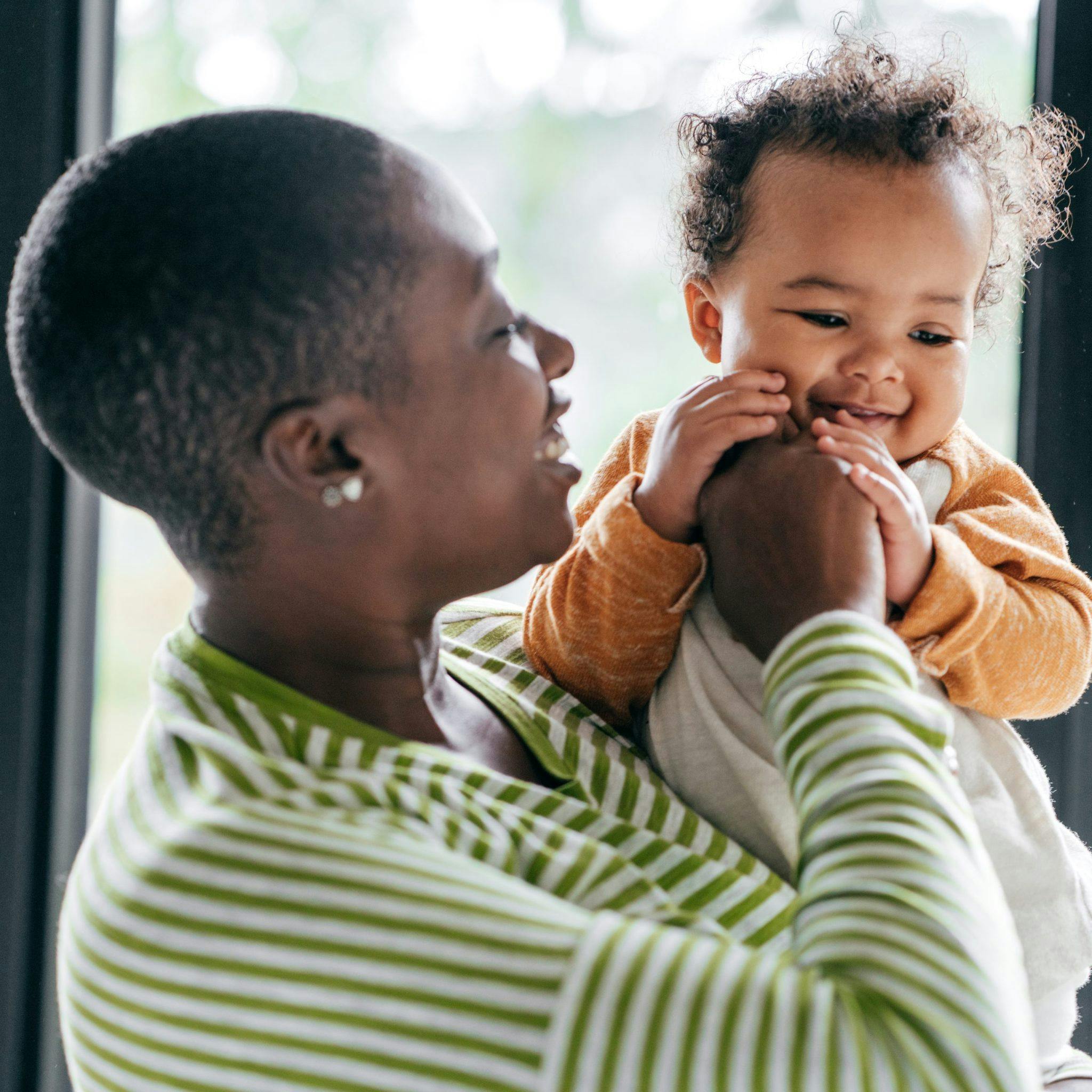 Person holding a smiling child with curly hair