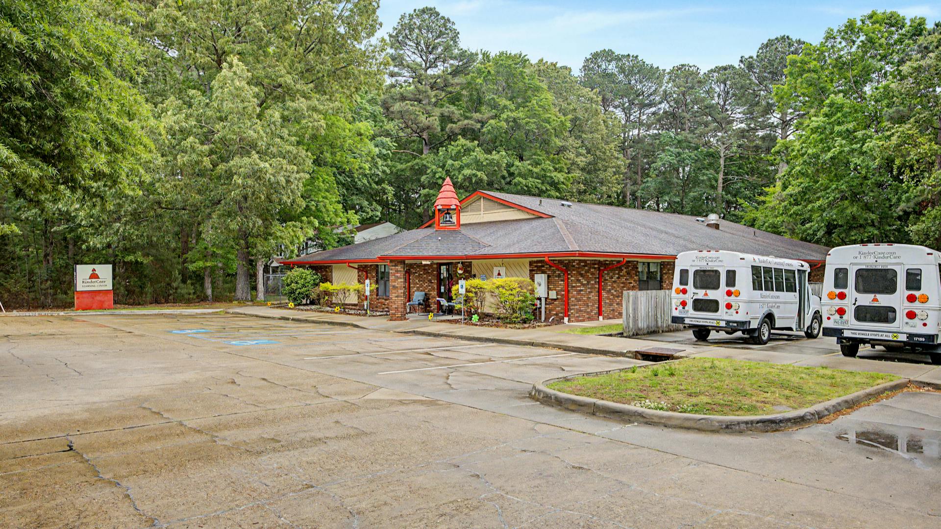 KinderCare Learning Center building with two white buses and a sign