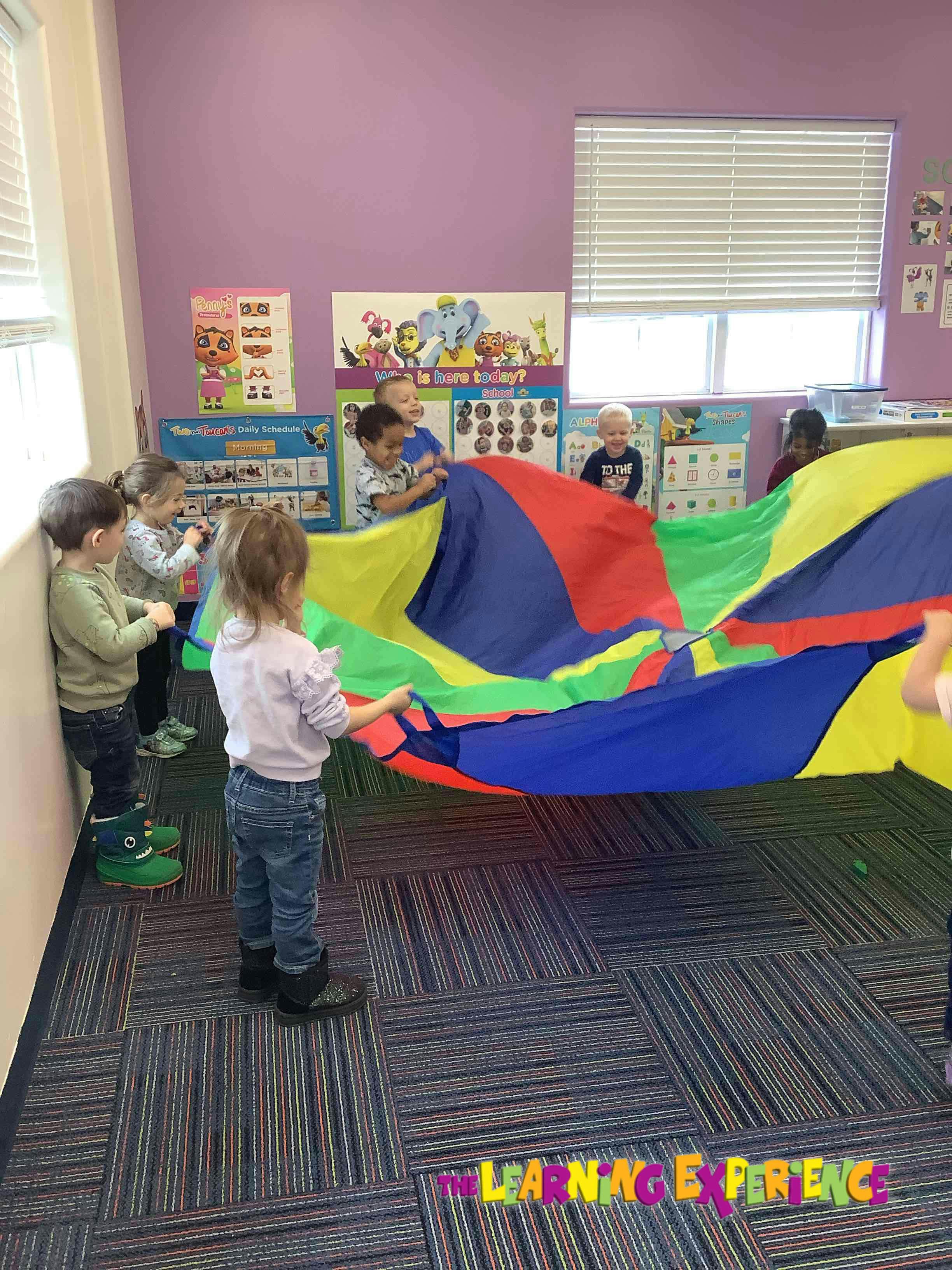 Children playing with a colorful parachute in a classroom