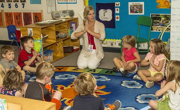 Adult and children sitting on floor in a classroom
