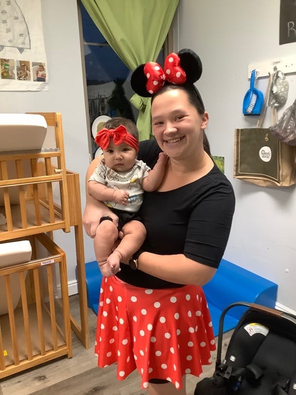 Person holding a child, both wearing red bows