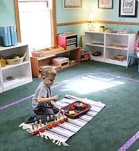 Child playing with toys on a rug in a classroom
