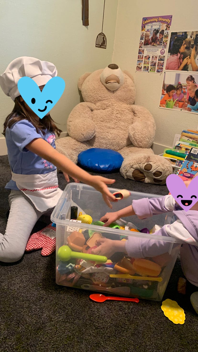 Child in chef hat and apron playing with toy food in a bin