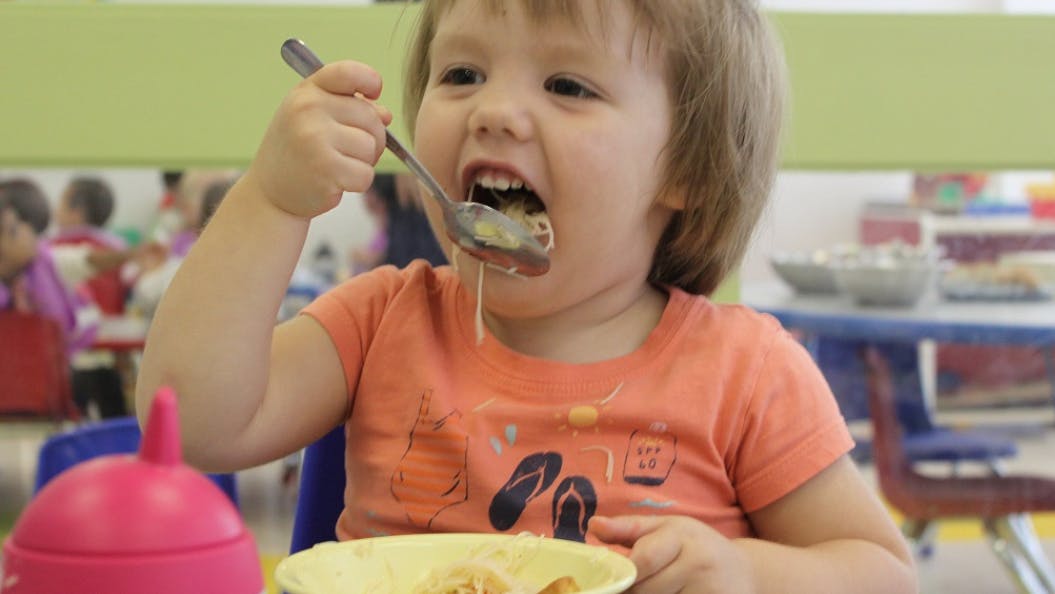 Child eating from a spoon in a classroom