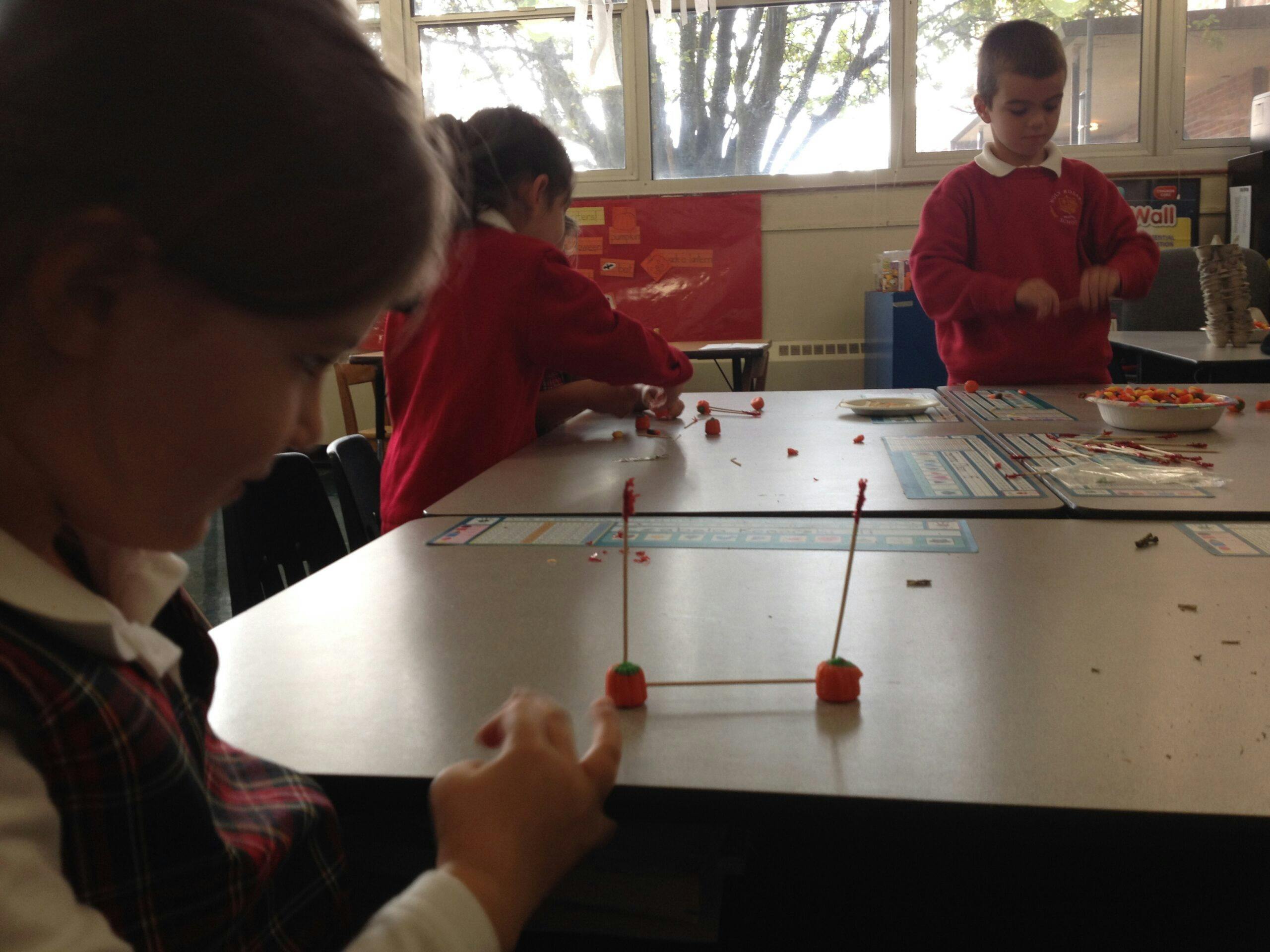 Children in a classroom working on a craft with candy corn and toothpicks