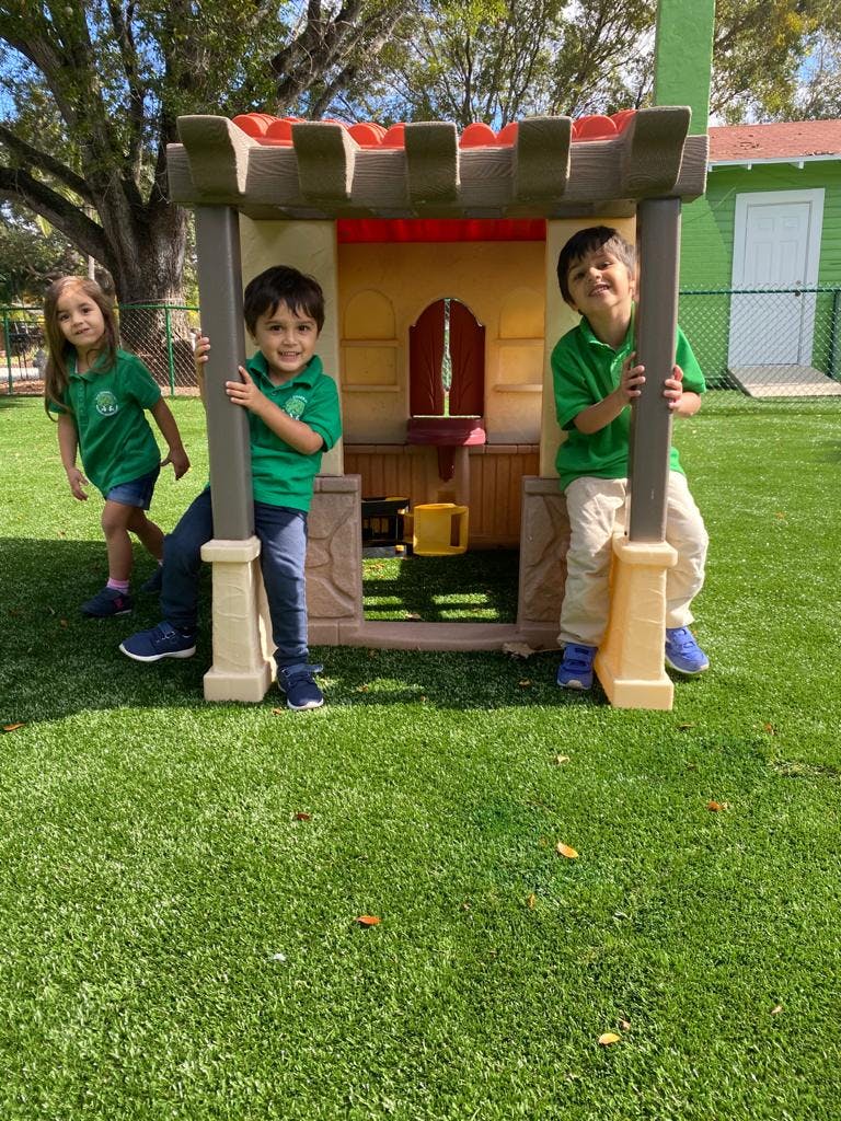 Three children playing around a small playhouse