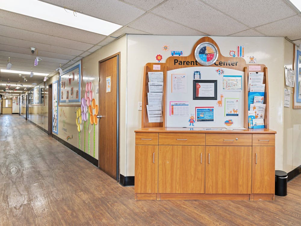Hallway with a wooden "Parent Center" cabinet and bulletin board
