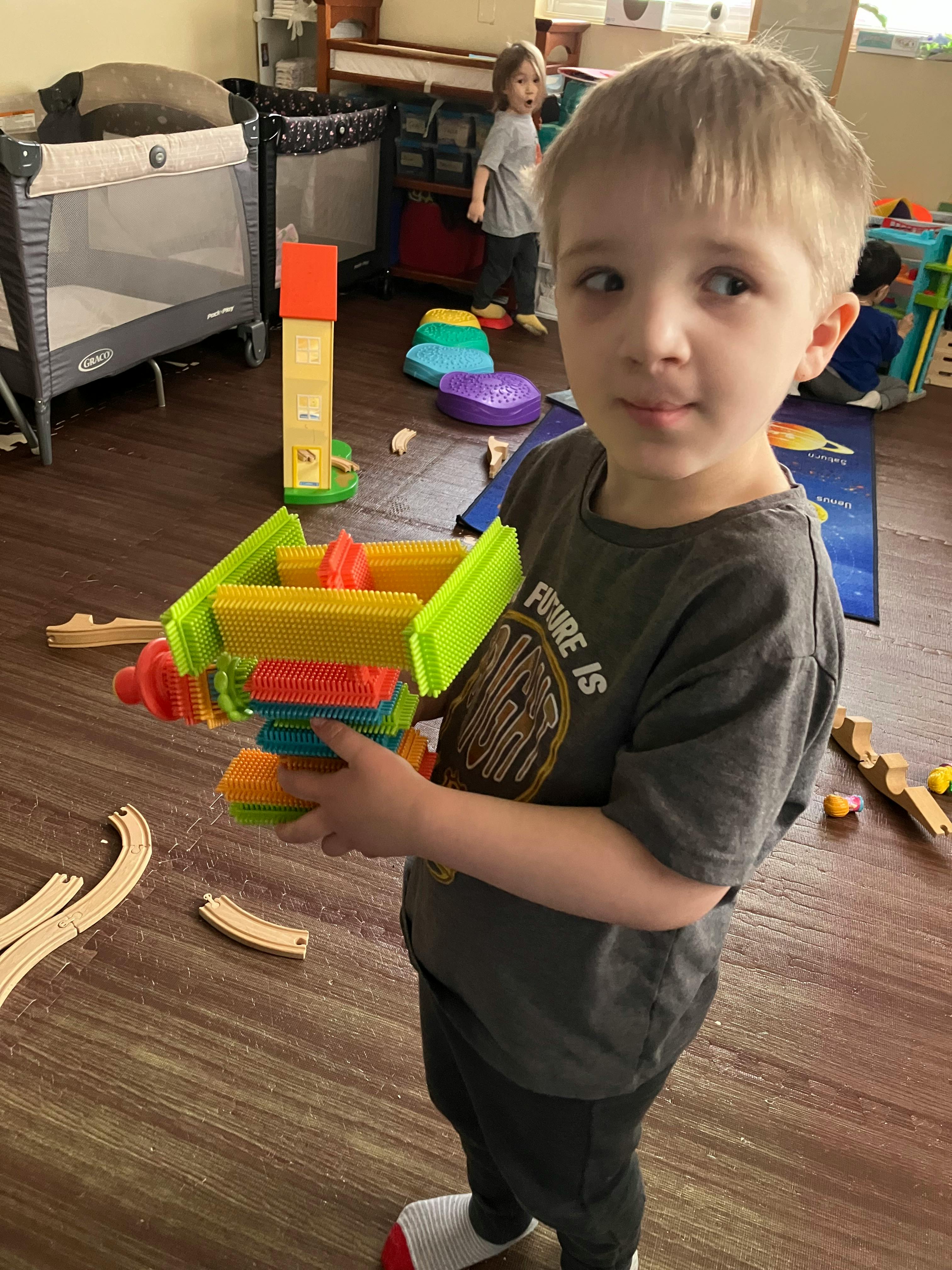 Child holding a colorful bristle block creation