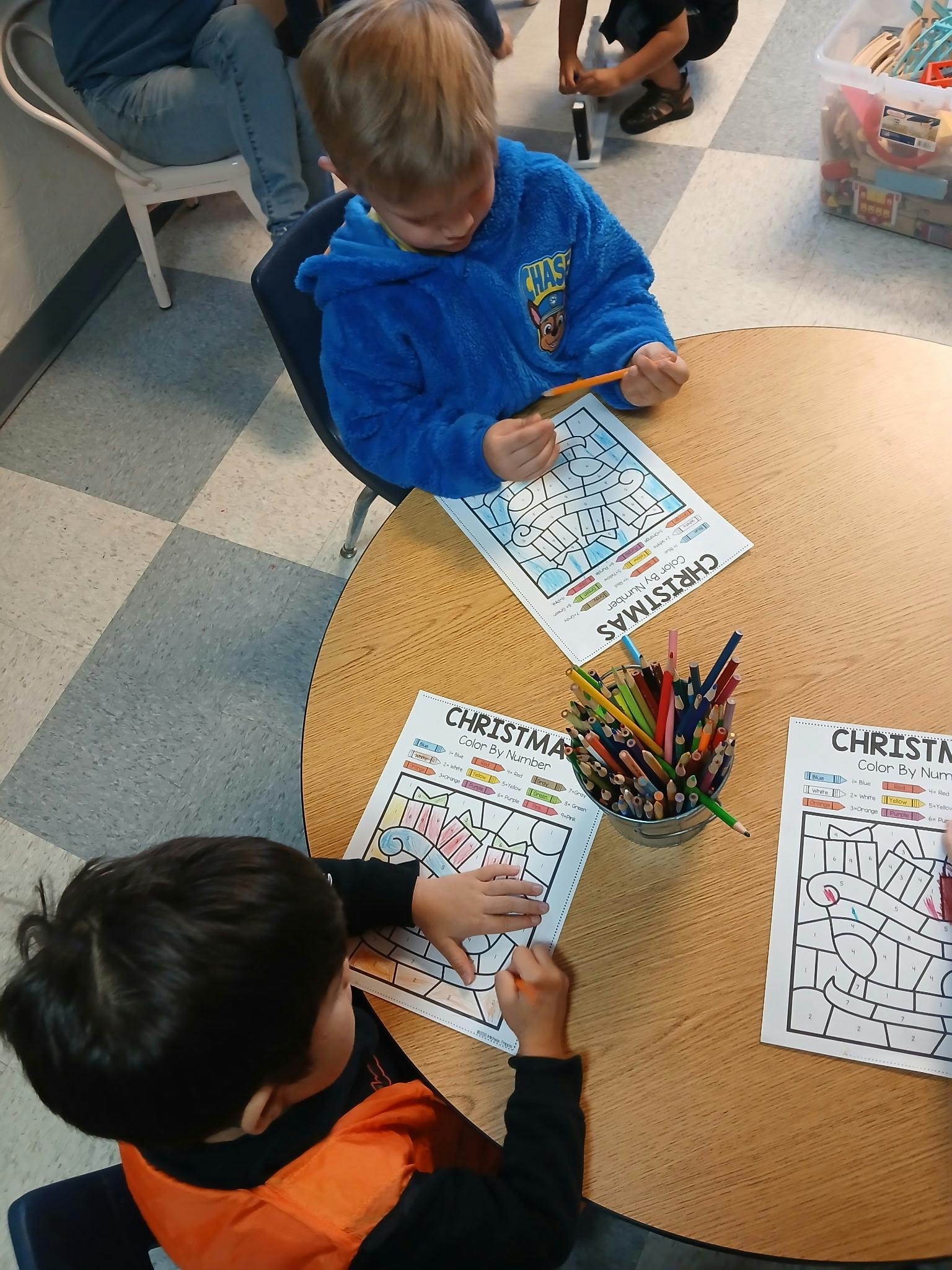Children coloring Christmas color-by-number pages at a round table