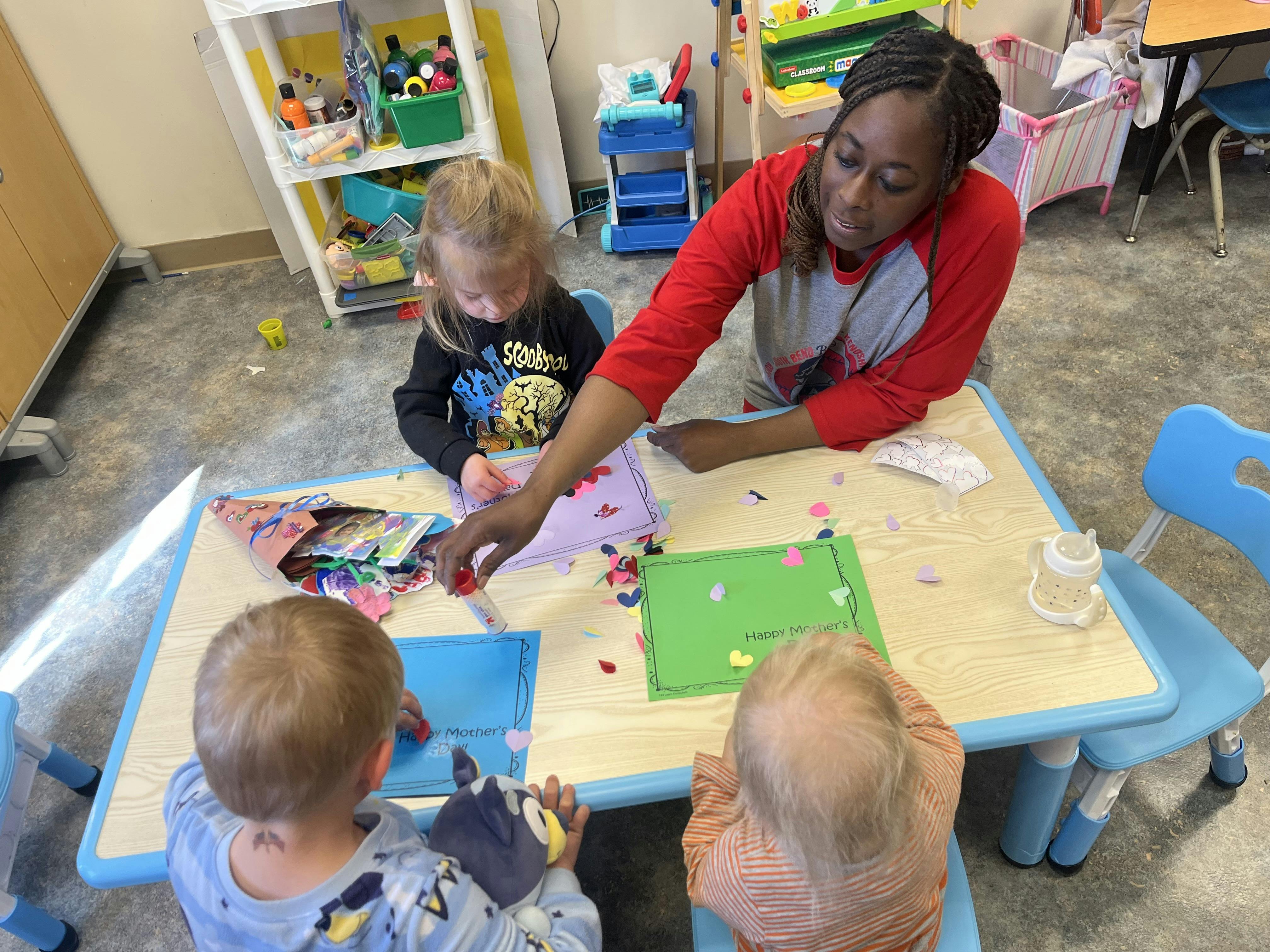 Teacher and three children decorating "Happy Mother's" cards