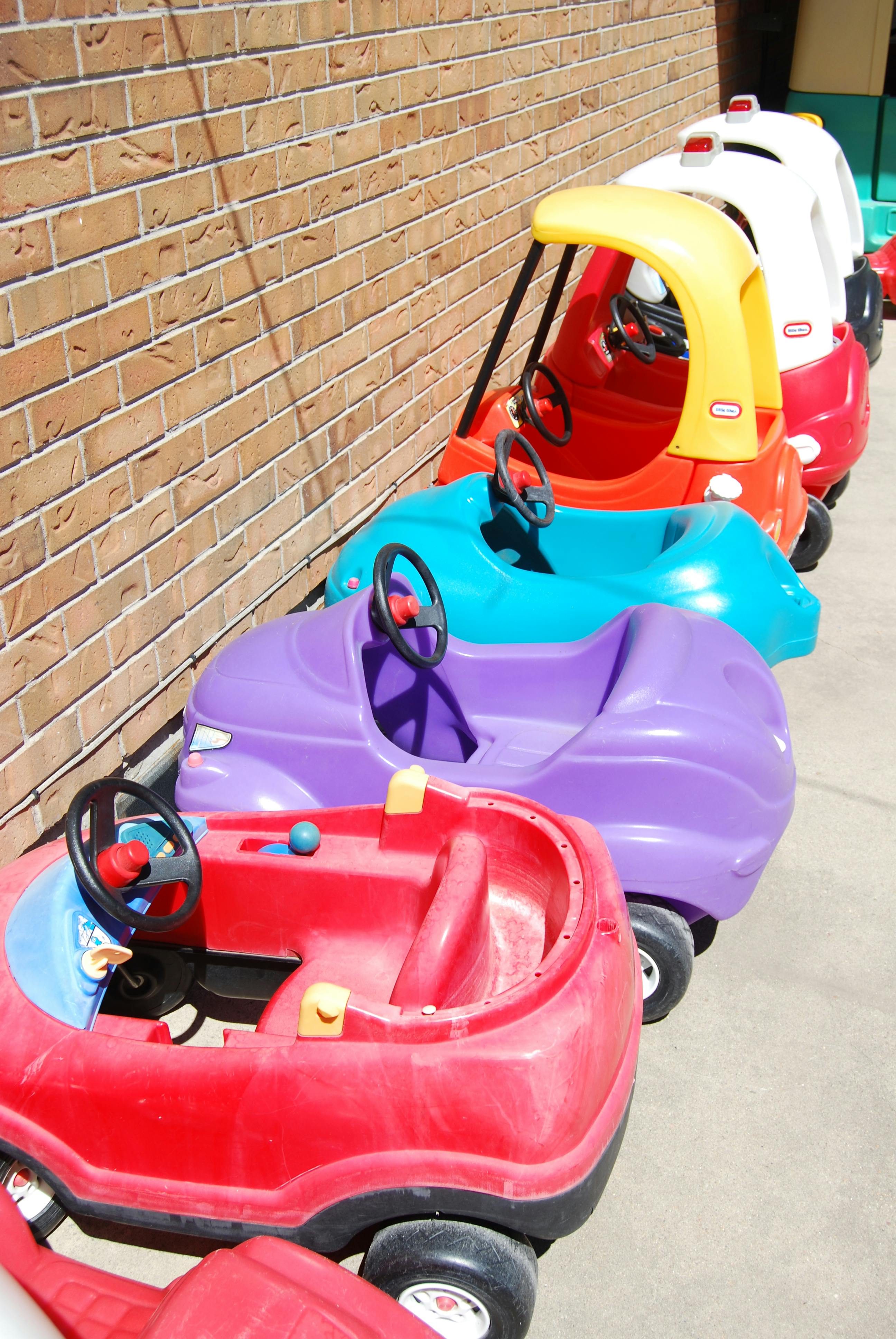 Row of colorful toy cars lined up against a brick wall