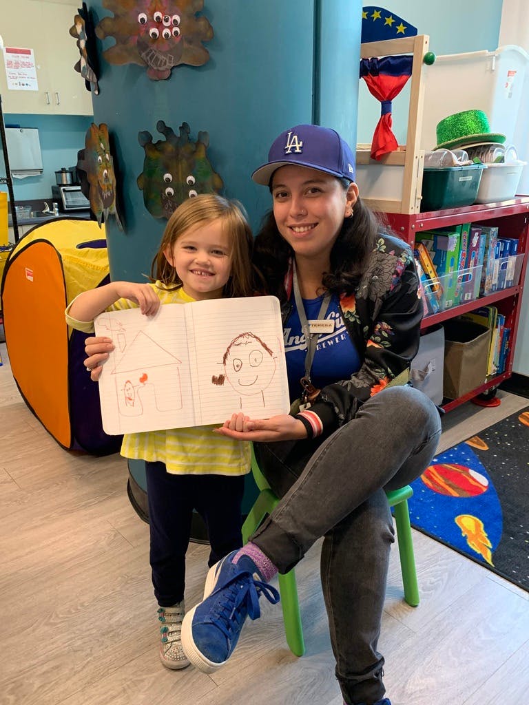 Child and person holding up a drawing in a classroom