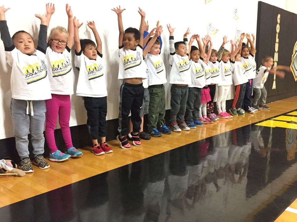 Group of children standing in a line with arms raised