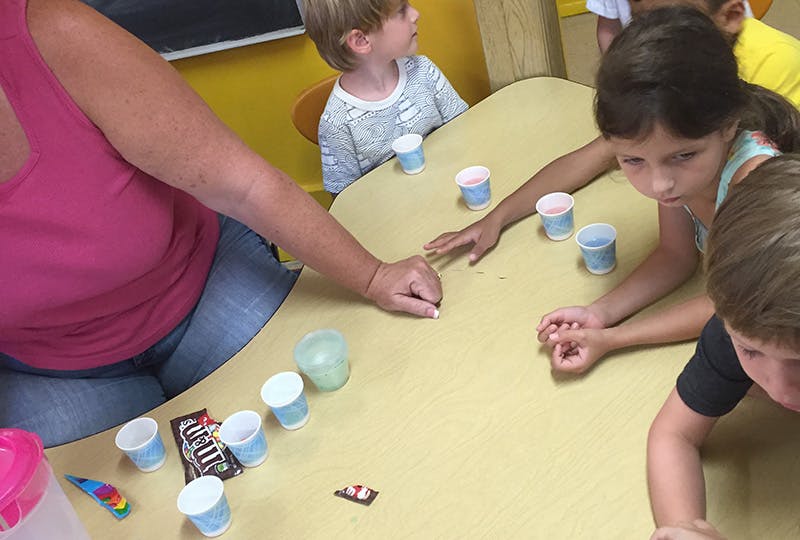 Adult and children at a table with small cups and candy