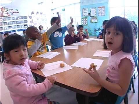 Children sitting at a table in a classroom, one child holding a small object