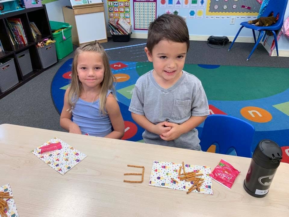 Two children sitting at a table in a classroom