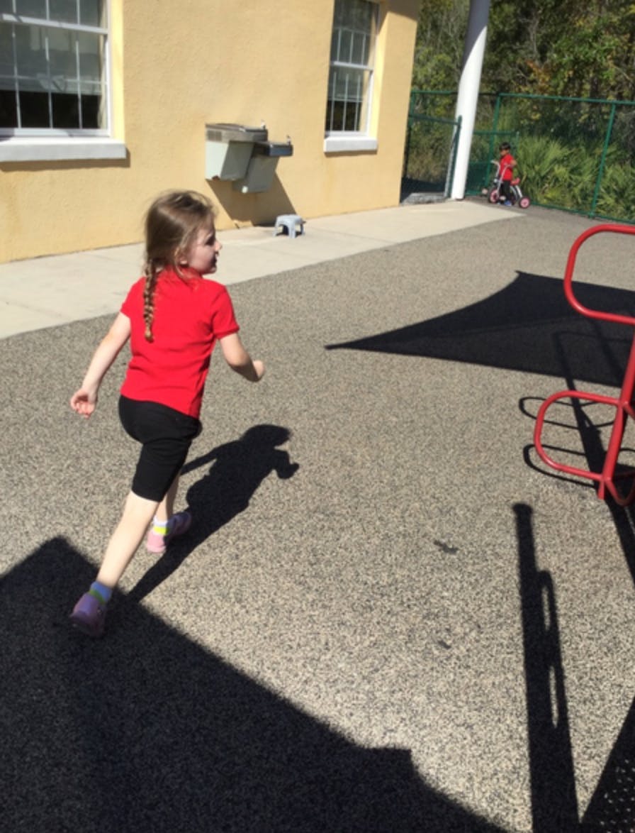 Child running on a paved surface outdoors