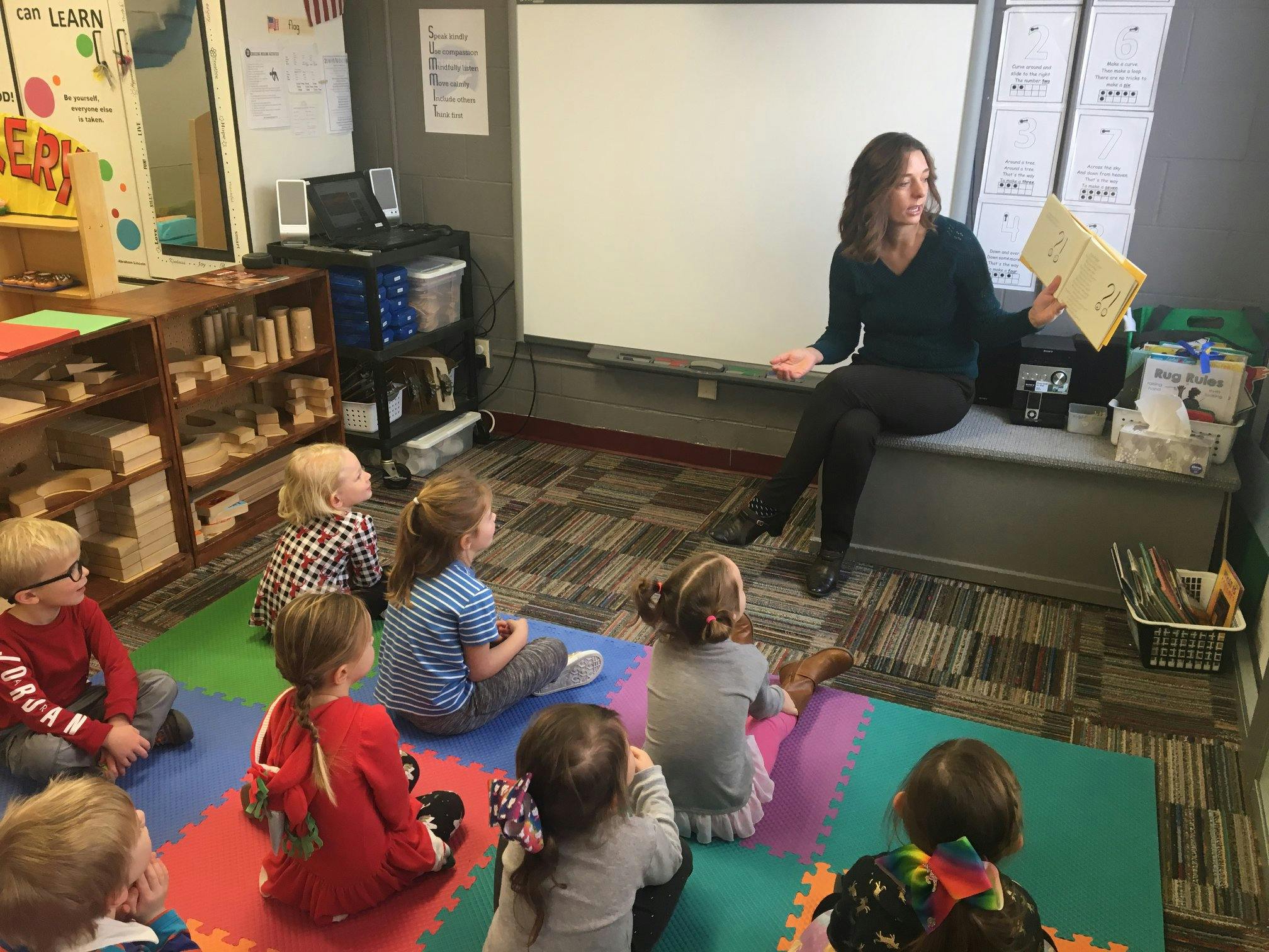 Adult speaking to children sitting on floor in classroom