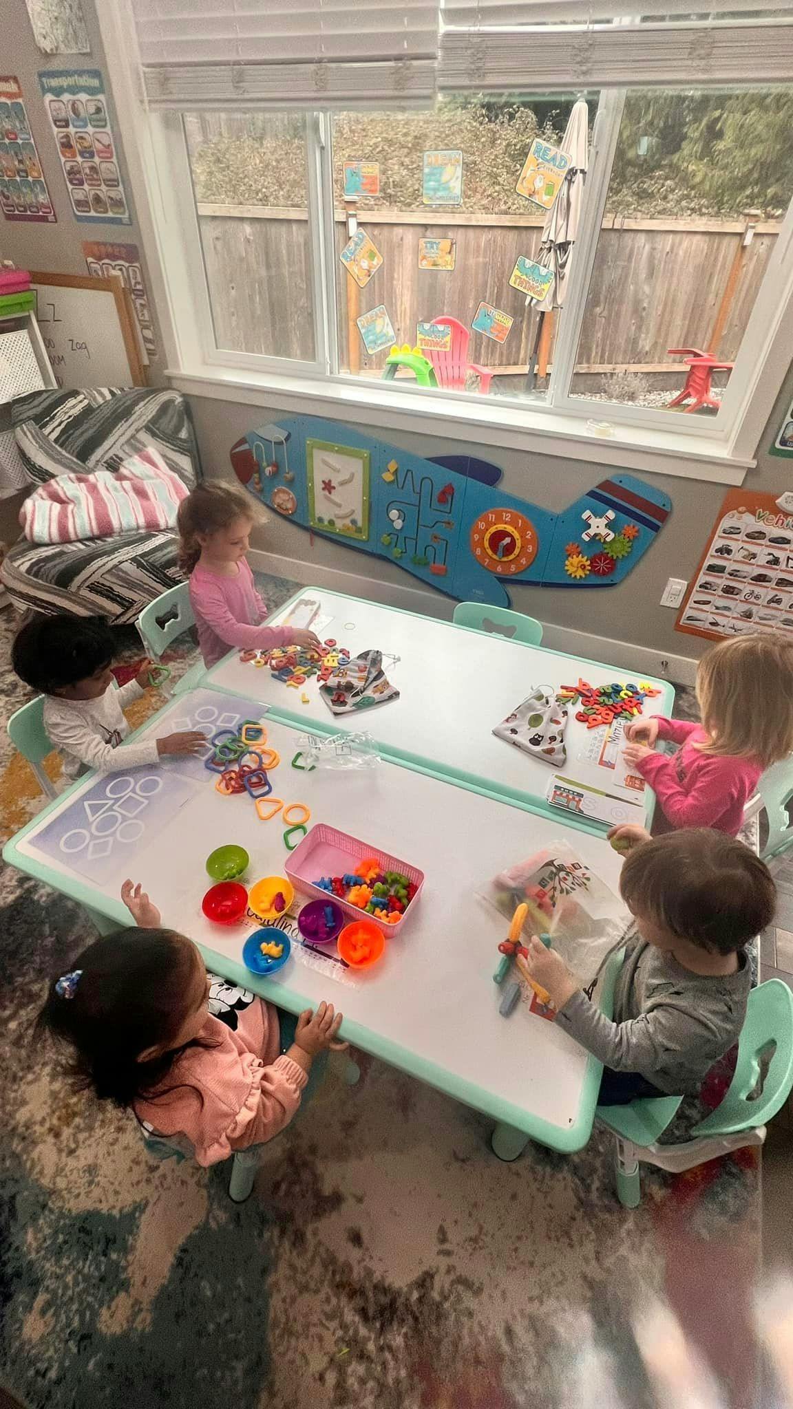 Children playing with colorful toys at a table in a classroom