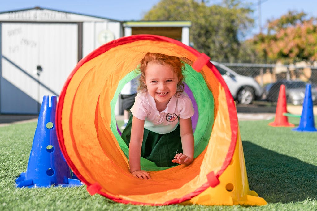 Child crawling through a colorful play tunnel