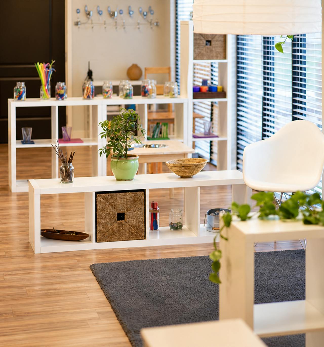 White storage shelving units with various decor and plants in a classroom