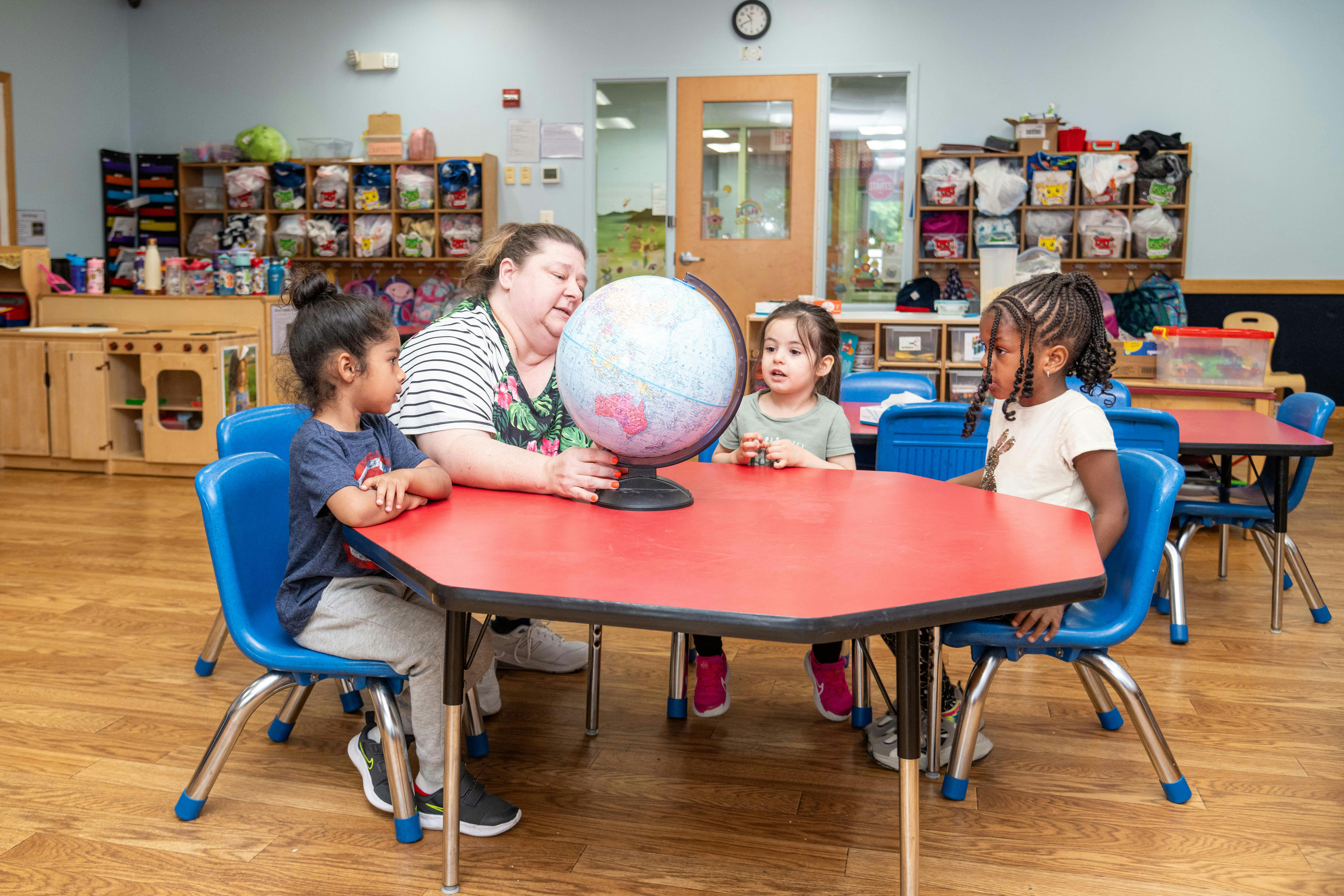 Adult and three children looking at a globe in a classroom