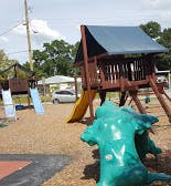 Playground with a wooden playhouse, slides, and a green animal-shaped spring rider