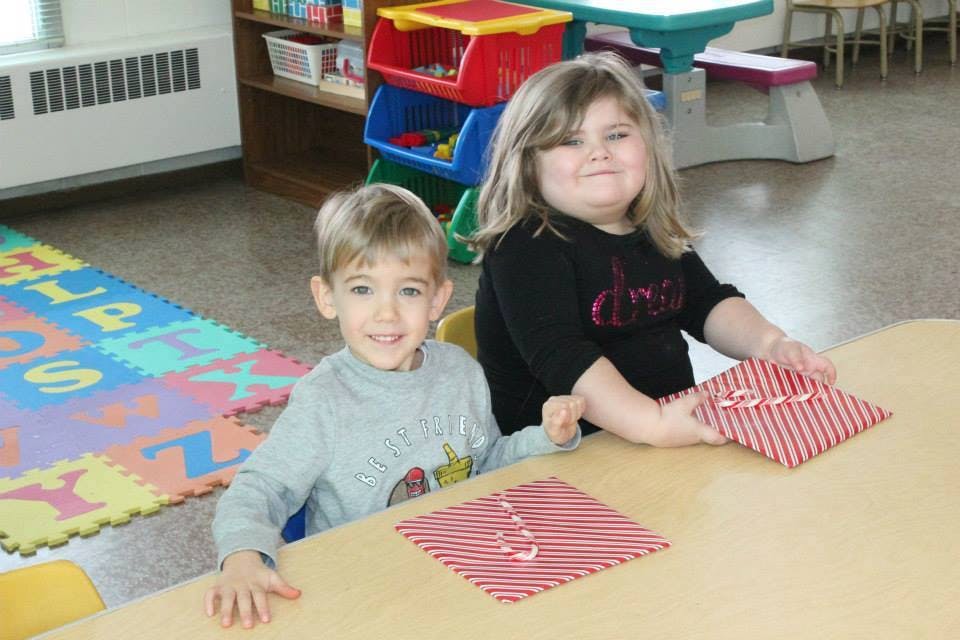 Two children at a table with striped paper