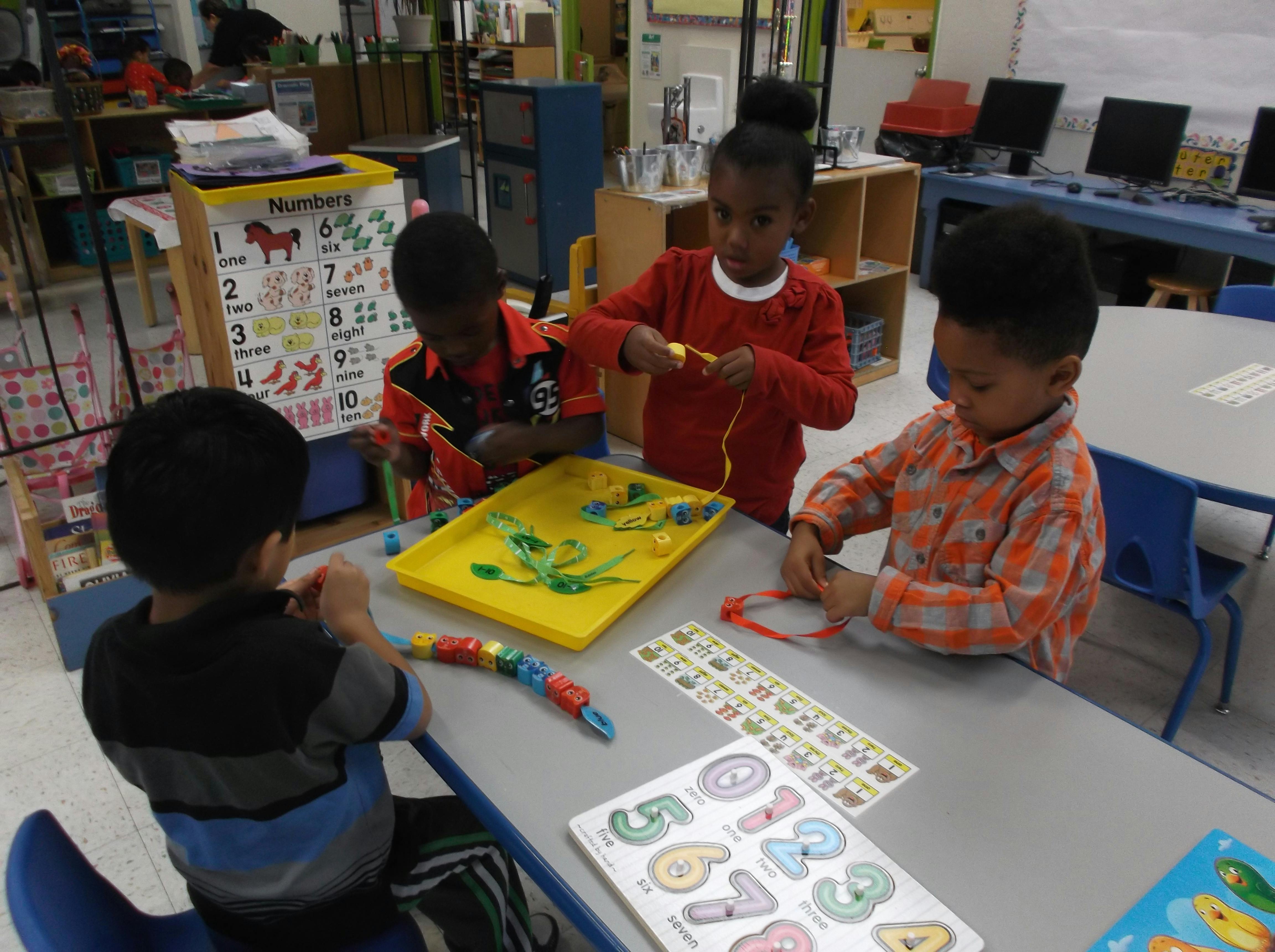 Four children at a table playing with learning toys in a classroom