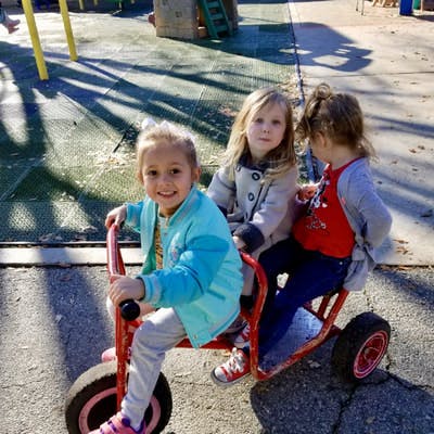 Three children on a red tricycle