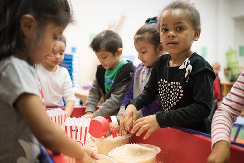 Children playing with rice and popcorn in a classroom