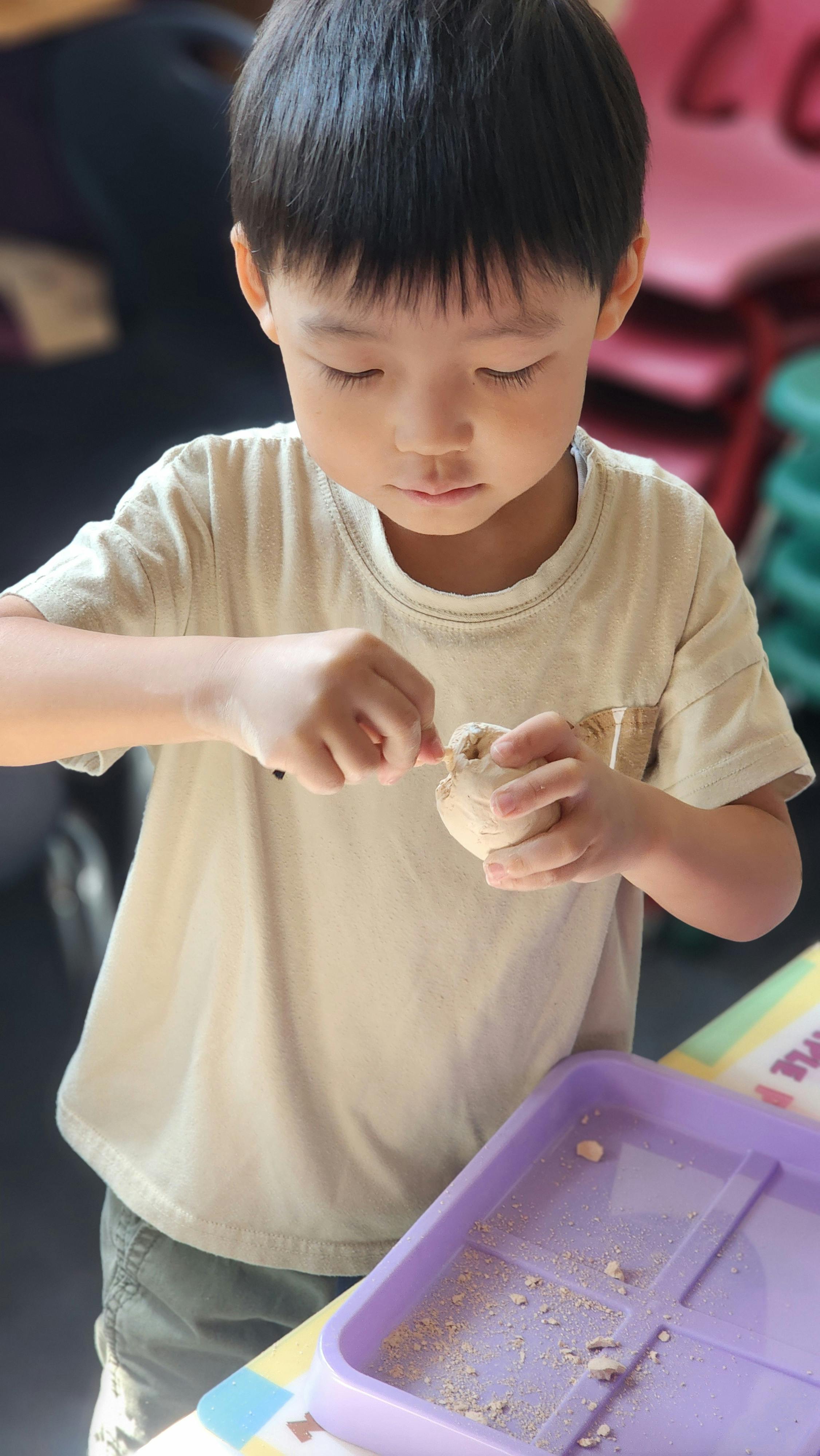Child carving into a small object with a tool