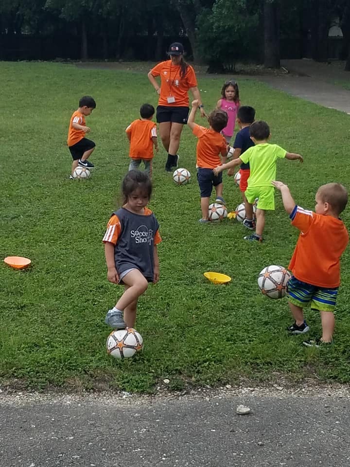 Adult and children playing soccer on grass