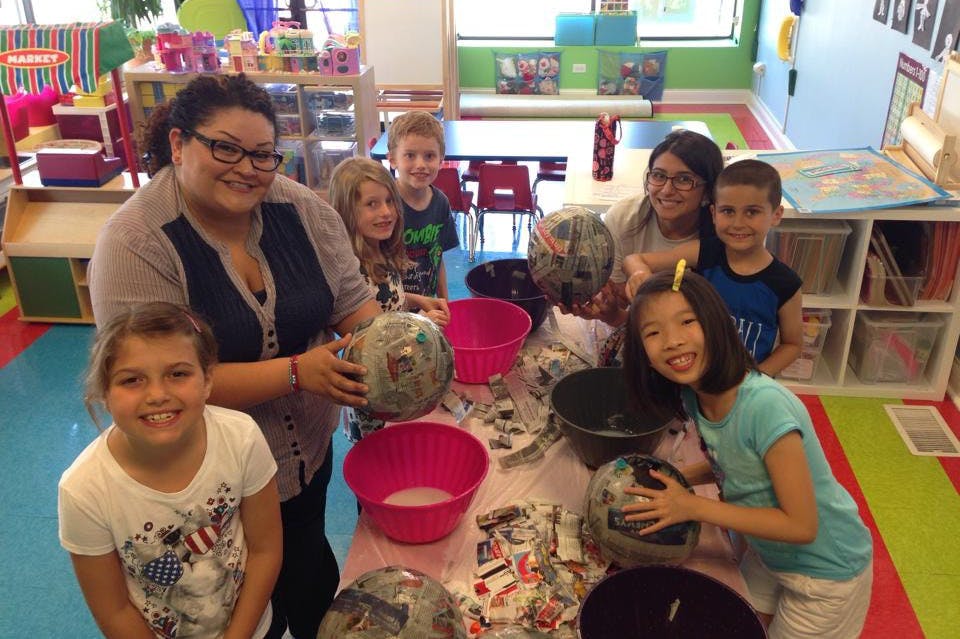Adults and children making paper mache crafts in a classroom