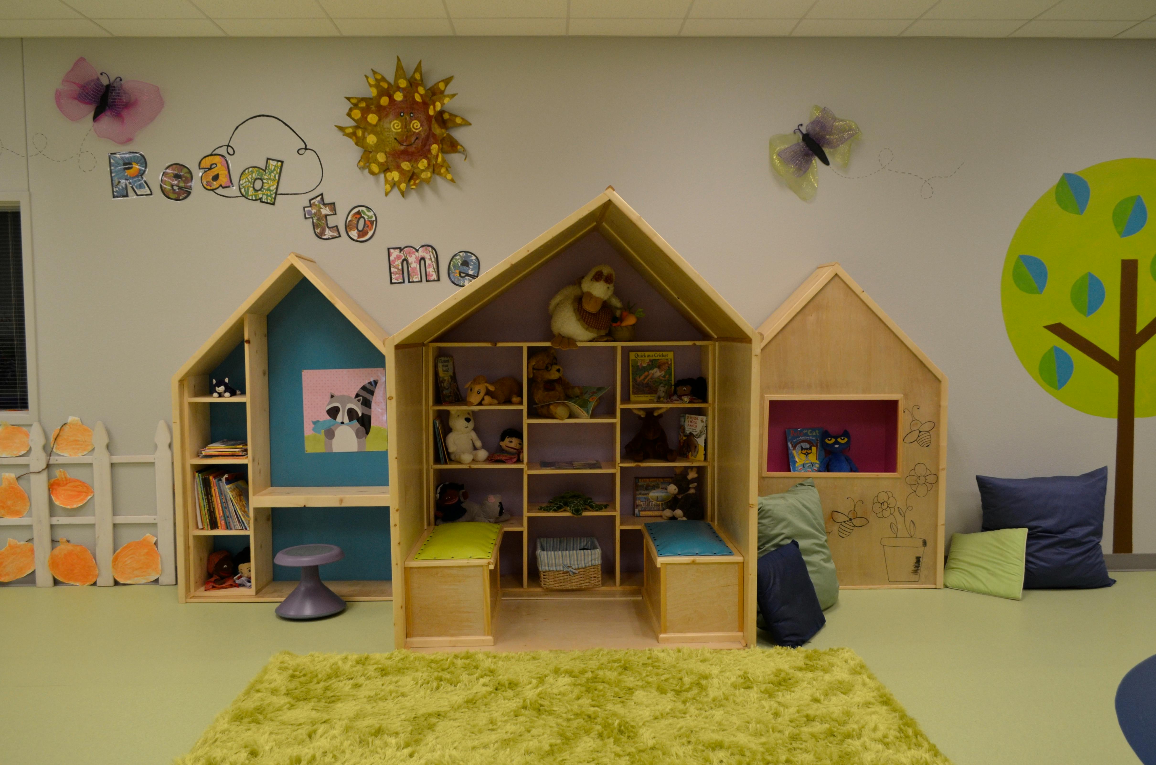 Children's play area with house-shaped shelves and a rug