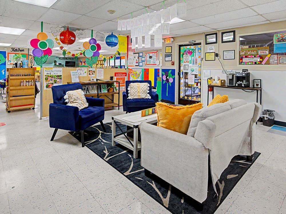 Lounge area in a classroom with two blue chairs and a light-colored sofa