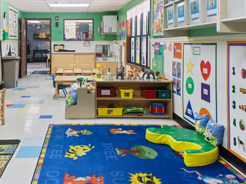 A children's classroom with small tables, chairs, and play areas