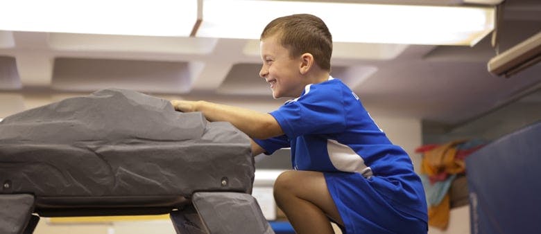 Child in blue shirt playing on soft play equipment
