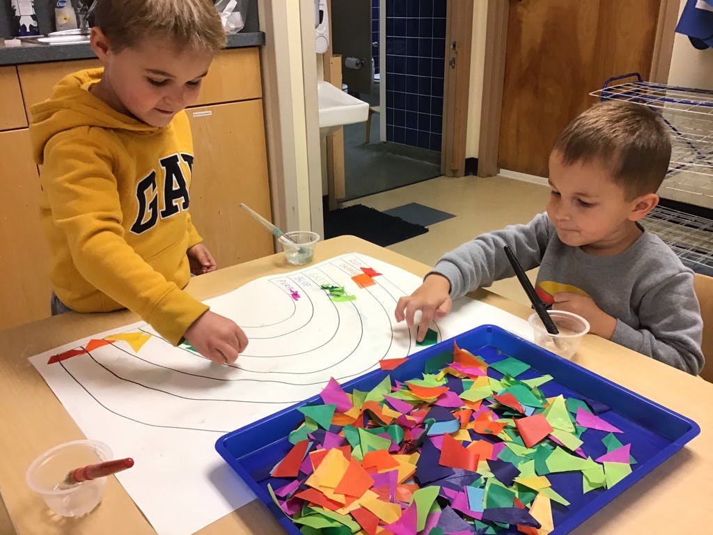 Two children doing an art project with colorful paper pieces