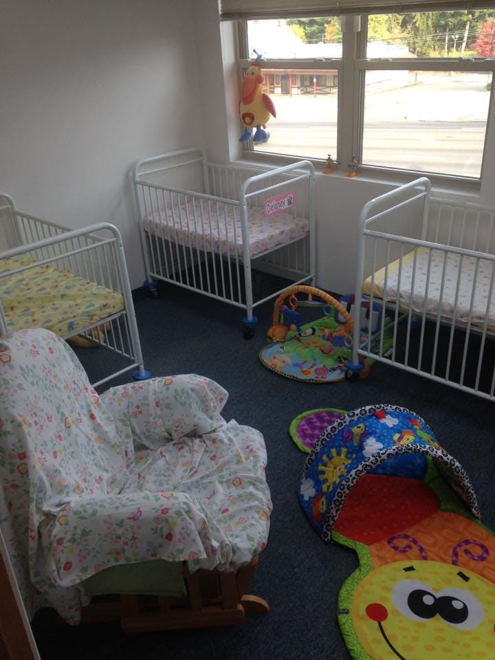 Three cribs, a rocking chair, and playmats in a room