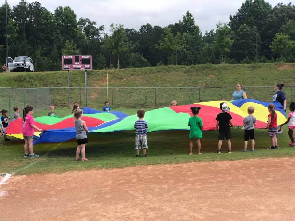 Children and adults playing with a large colorful parachute on a field